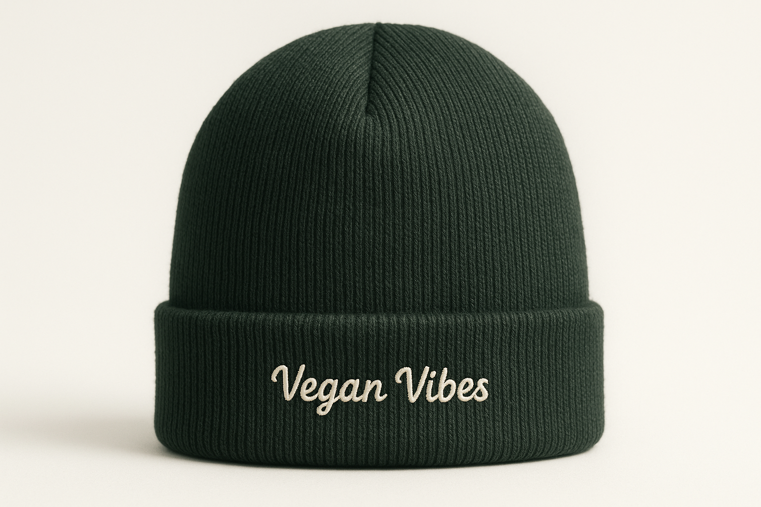 Nahaufnahme eines dunkelgrünen Bio-Beanies, sauberer Strick, kleiner Frontschriftzug „Vegan Vibes“. Neutraler heller Hintergrund, sanftes Tageslicht, E-Commerce-Freisteller, hohe Detailgenauigkeit.